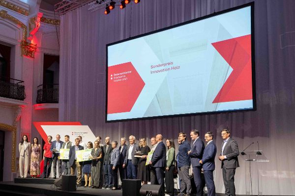 Eine Gruppe von Menschen steht auf der feierlichen Bühne der Sofiensäle - auf der Leinwand steht Sonderpreis Innovation Holz
