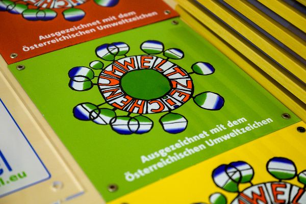 Emaille-Tafeln des Österreichischen Umweltzeichens in rot, grün und gelb.