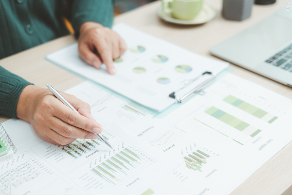 Person analysiert Tabellen und Grafiken mit Kreis- und Balkendiagrammen.