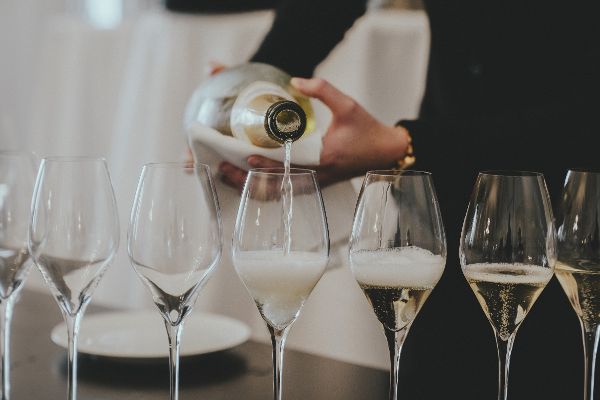 Ein Person schenkt aus einer Sektflasche Sekt in Sektgläser ein.