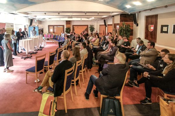 Personen auf Sesseln die Richtung Vortragenden schauen