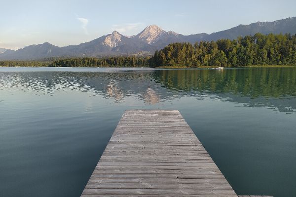 Auf dem Bild ist der Faakersee und im Hintergrund Berge zu sehen