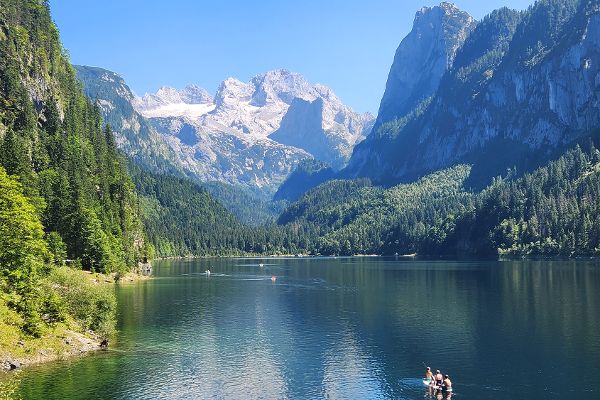 Auf dem Foto ist ein See, mit beschneiten Bergen im Hintergrund bei strahlendem Sonnenschein zu sehen