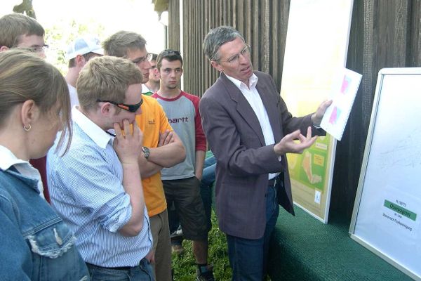 Discussion in front of a board outdoors, at the back of a barn