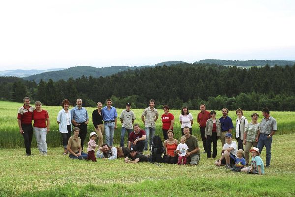 A group of people on a green meadow, with a wooded range of hills in the background