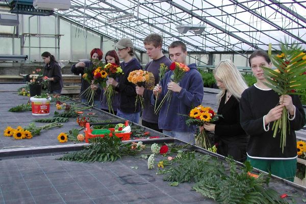 Students in a greenhouse arranging flower bouquets