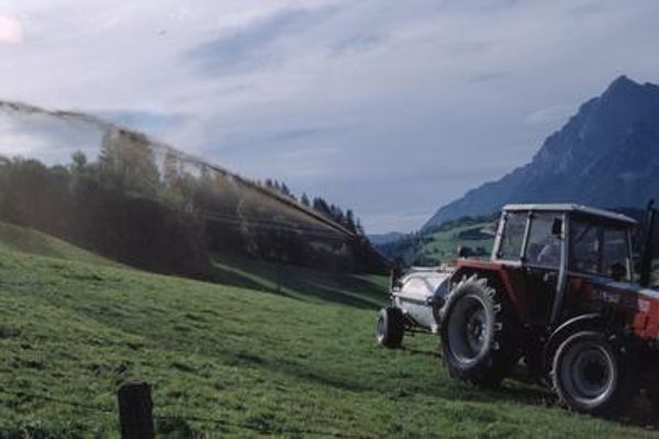 Liquid manure spreading with pressure tank and side discharge