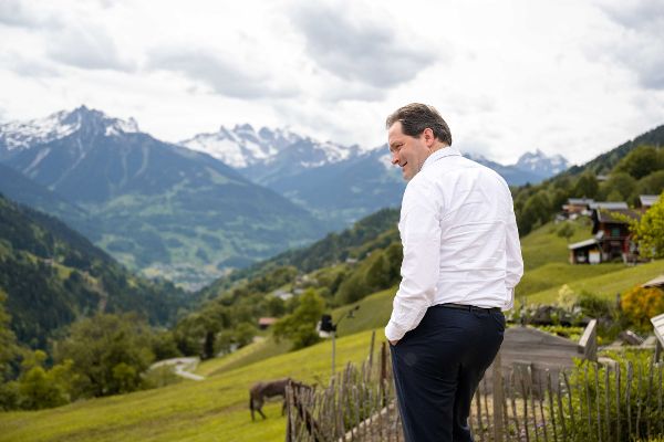 Totschnig steht auf einer Alm mit Blick auf Berge