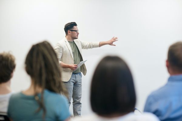 Lehrer erklärt am Whiteboard jugendlichen Schülerinnen und Schülern Lehrinhalte