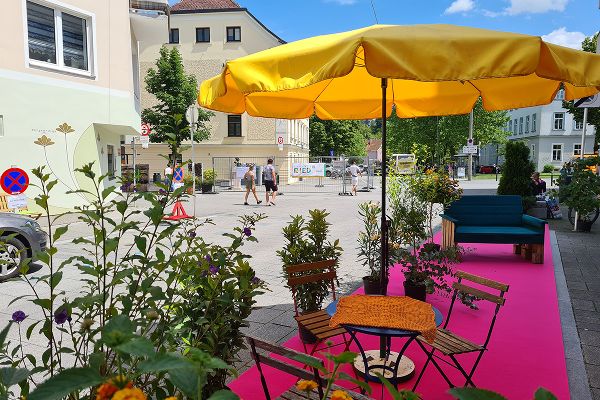 Gartenmöbel und selbst gestaltete Möbel auf rosa Teppich im öffentlichen Raum