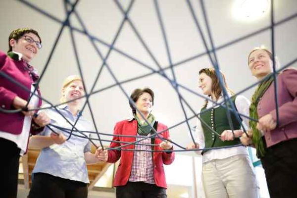 Fünf Frauen stehen im Kreis und halten ein Netz