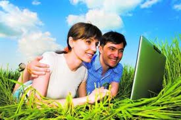 Mann und Frau liegend in einer Wiese mit einem Laptop