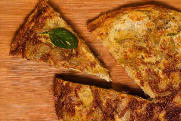 Spanische Tortilla, ein Stück ist bereits herausgeschnitten und liegt daneben