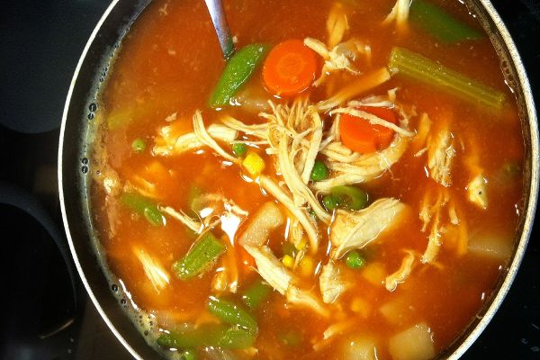 Topf mit Hühnersuppe, Gemüse und Kräutern