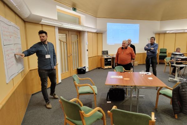 Ein Mann präsentiert die Ergebnisse seiner Workshopgruppe der restlichen Teilnehmerinnen und Teilnehmer.