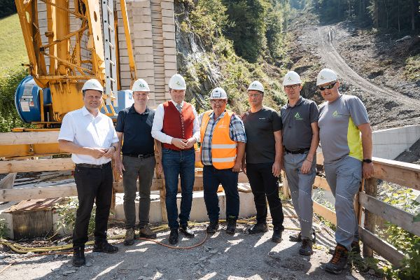 Gruppenfoto der Pressekonferenz Rot-Weiß-Rot Bauen: Landeshauptmann-Stellvertreter Josef Geisler, Bürgermeister Hans Jörg Moigg, Bundesminister Norbert Totschnig, Vorsitzender der Gewerkschaft Bau-Holz Josef Muchitsch, Bürgermeister Friedrich Steiner, Sektionsleiter Tirol der Wildbach- und Lawinenverbauung Gebhard Walter und Abteilungsleiter Wildbach- und Lawinenverbauung Florian Rudolf-Miklau (von links nach rechts) 