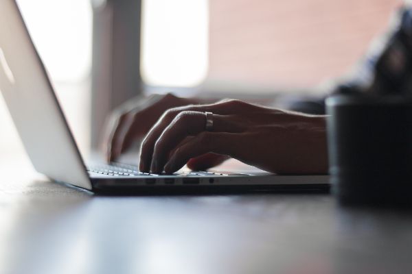Hände die auf einem Laptop schreiben