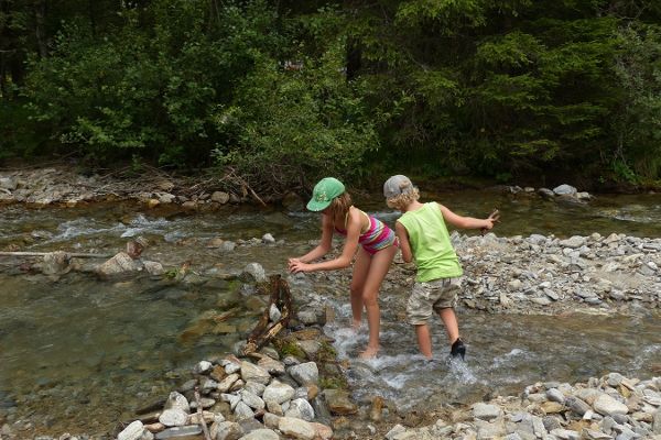 Das Foto zeigt im Wasser stehende, spielende Kinder am Bach