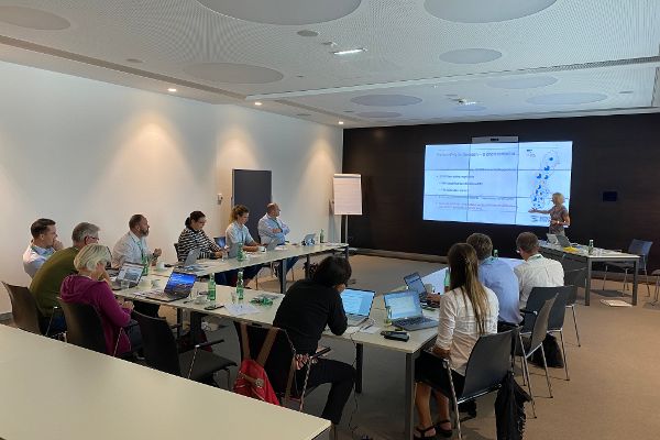 Saal mit Videoleinwand und 12 Personen beim Workshop