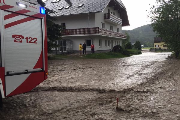 Überschwemmung vor einem Haus mit Feuerwehrauto.