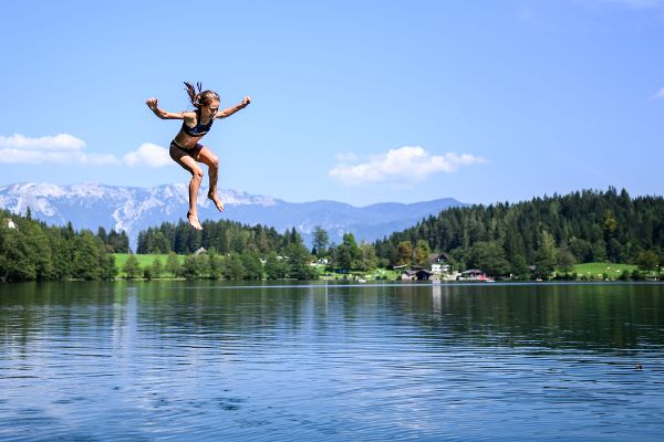 Ein Mädchen springt in einen See.