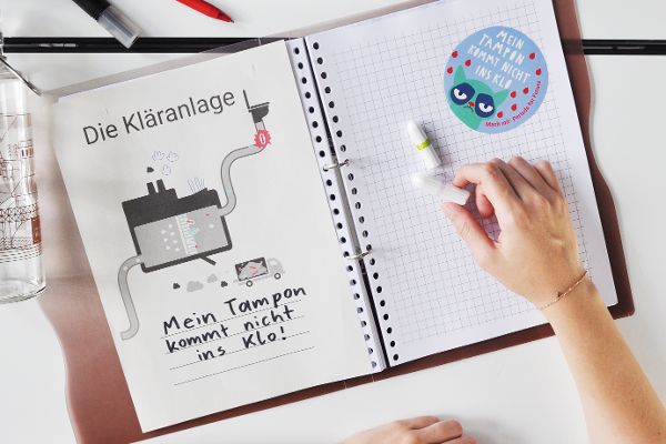 Auf dem Foto ist eine verstopfte Kläranlage zu sehen sowie der Spruch: Mein Tampon kommt nicht ins Klo.