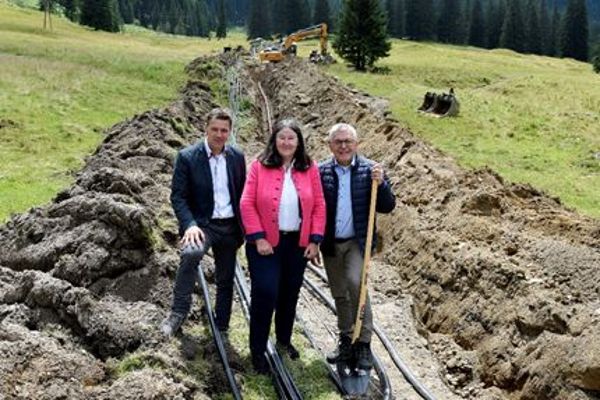  drei hochrangige Persönlichkeiten beim Spatenstich umgebenen von grüner Landschaft