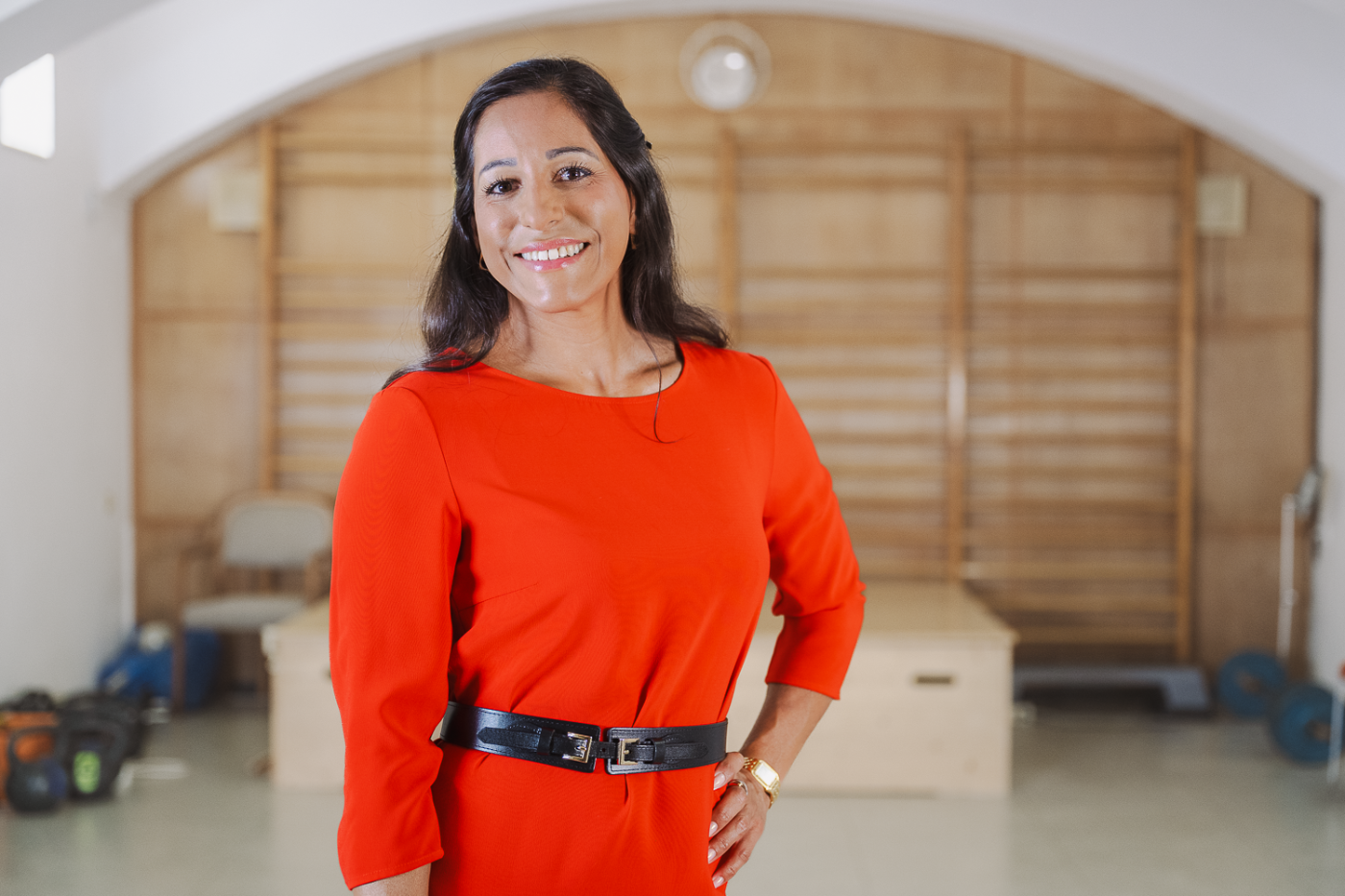 Frau mit dunkeln Haaren und rotem Kleid lächelt in die Kamera