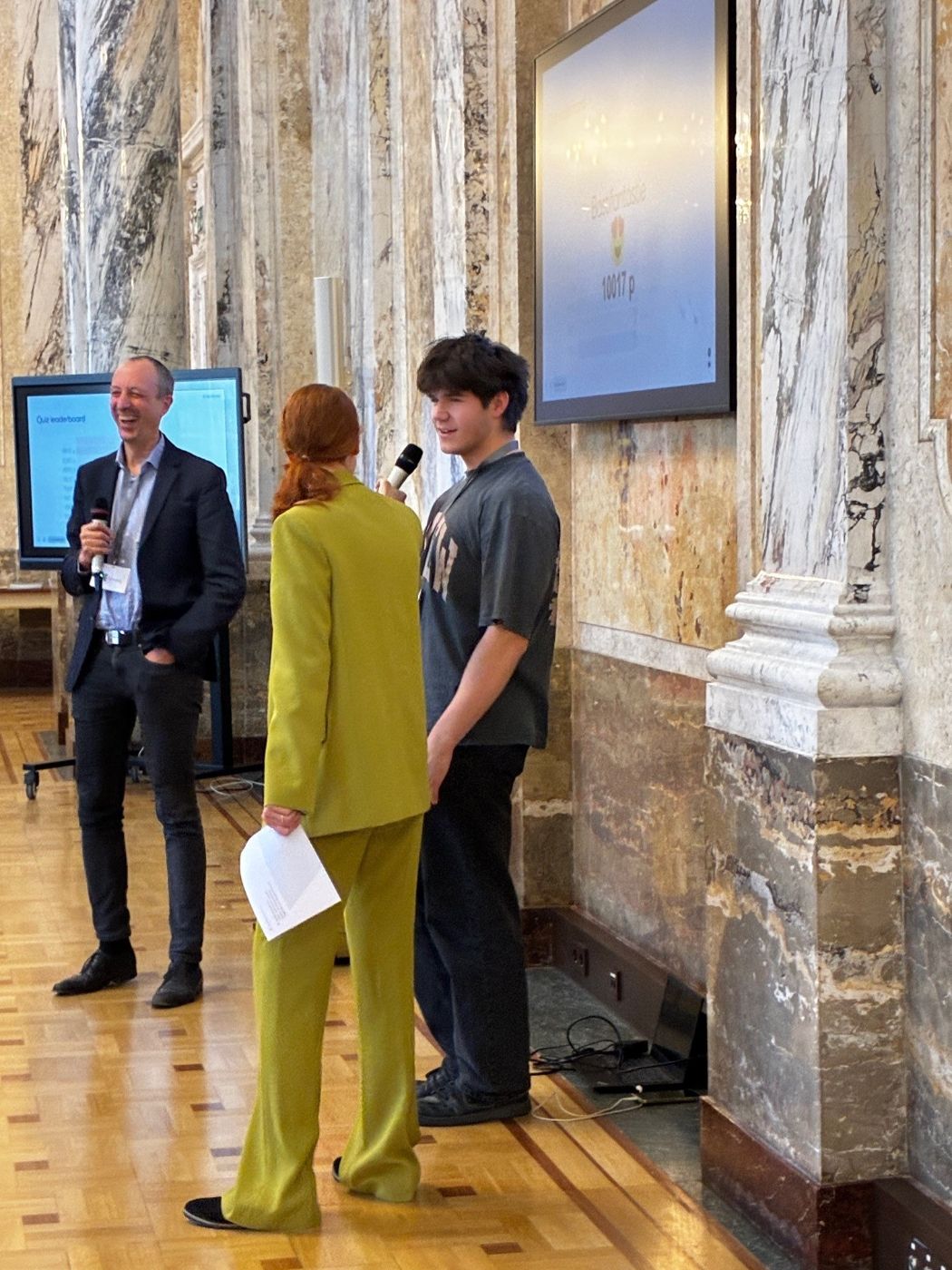 Am Foto sieht man den Sektionschef Jürgen Schneider, die Moderatorin Niki Löwenstein und den Gewinner des Schüler:innen Quiz