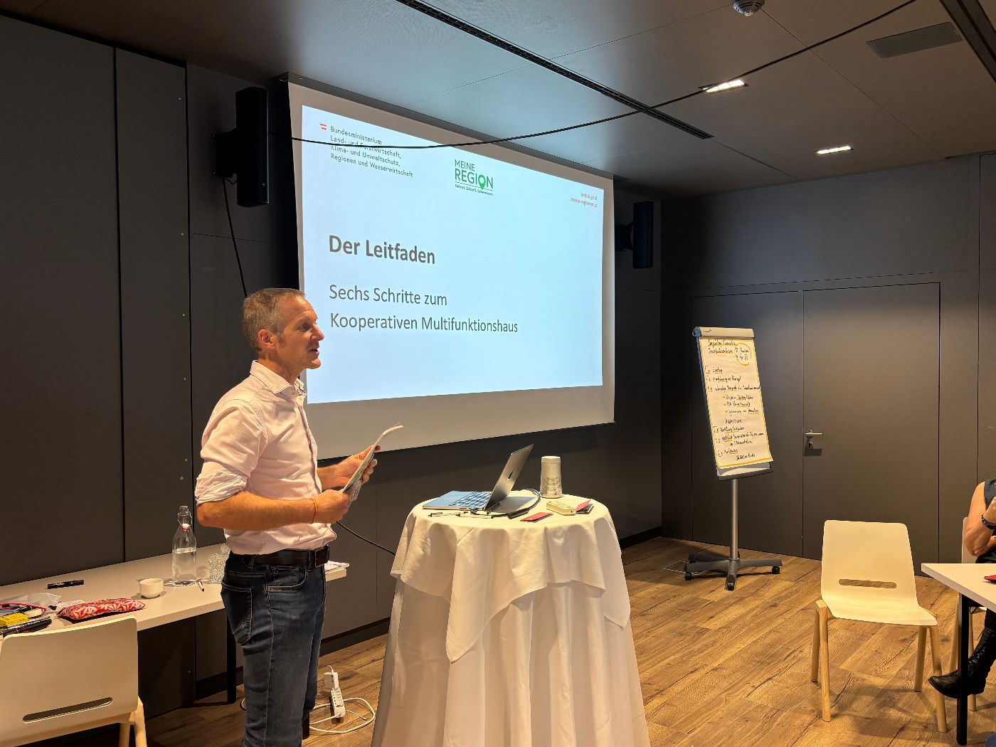 Zu sehen ist der Vortragende, im Hintergrund die Präsentation des Vortrags