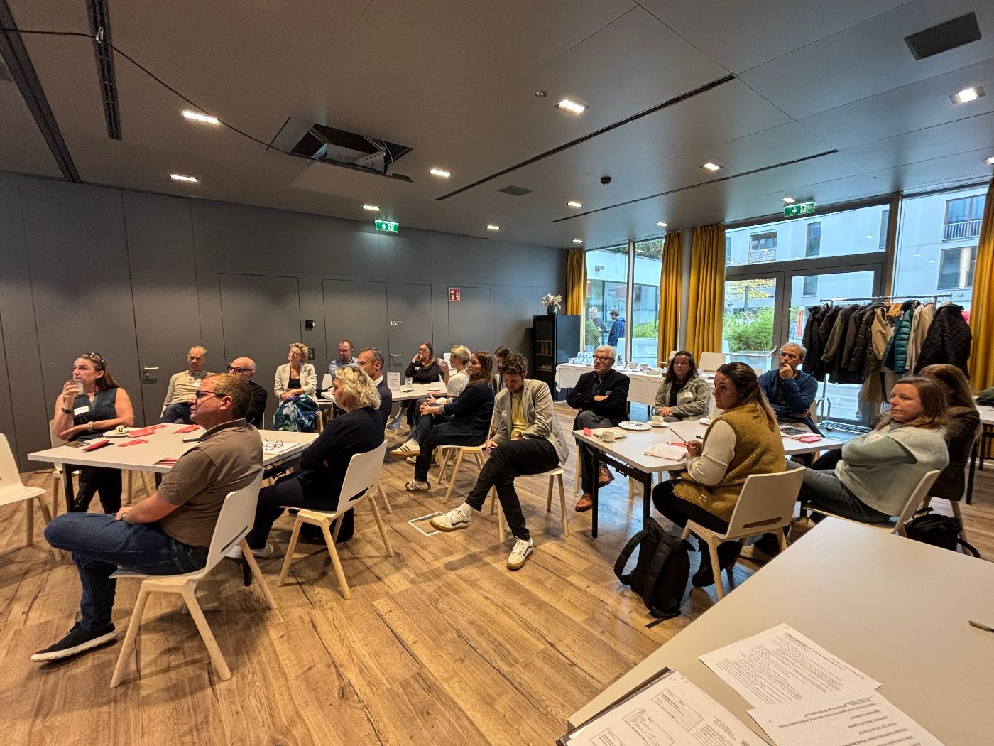 zu sehen sind die teilnehmenden, wie sie an Arbeitstischen sitzen