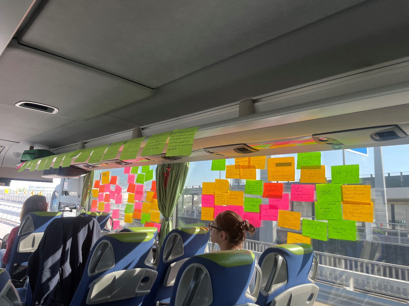 Zu sehen ist die Innenansicht eines Busses. Auf dem Fenster sind Postits aufgeklebt. 