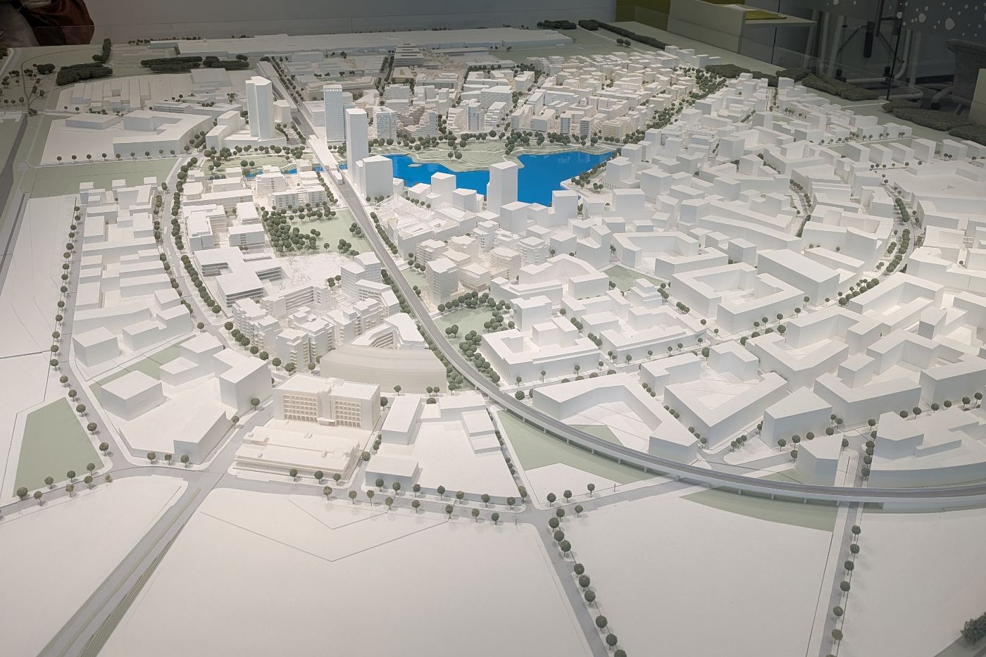 Detailliertes Architekturmodell der Seestadt mit Gebäuden, Straßen, Bäumen und einem zentralen See