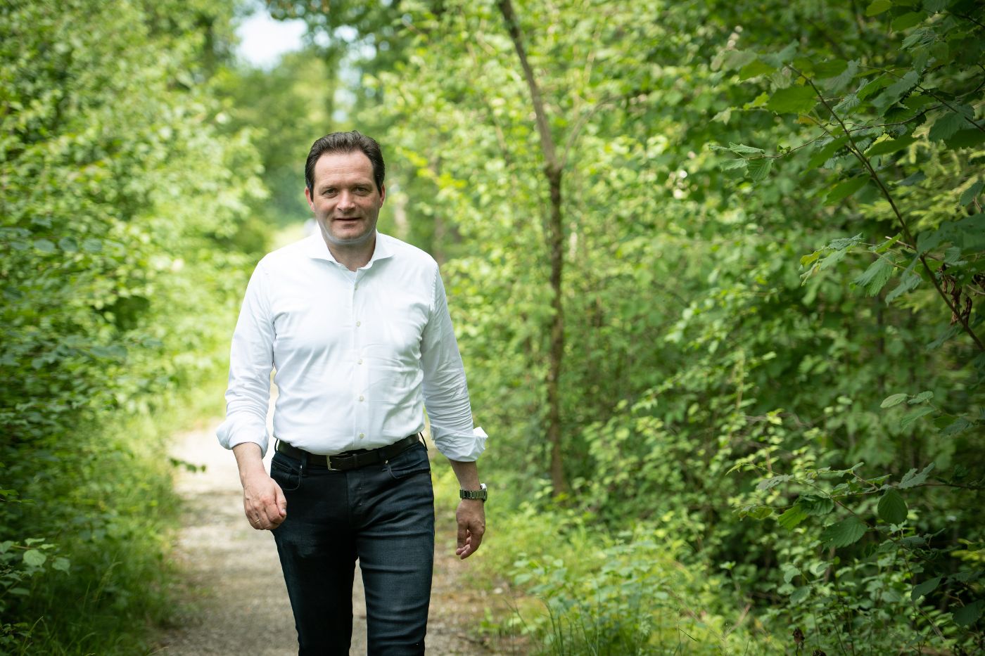 Minister Totschnig hemdsärmelig auf einem Waldweg