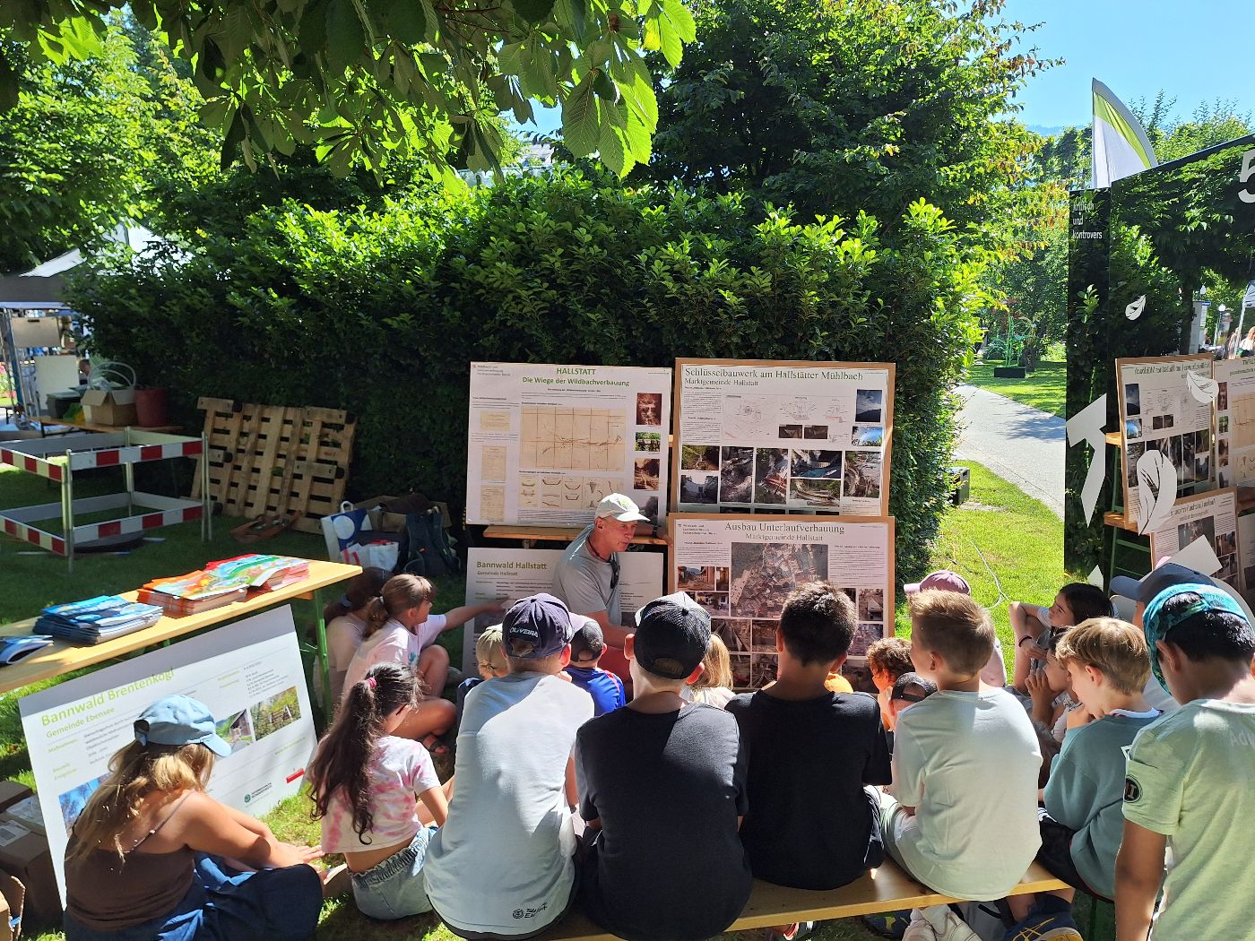 Schüler und Schülerinnen besuchen den Wassererlebnistag „Unser Wasserschatz“ in Bad Ischl während ein Mitarbeiter der Wildbach- und Lawinenverbauung Schutzmaßnahmen in der Umgebung vorstellt. 