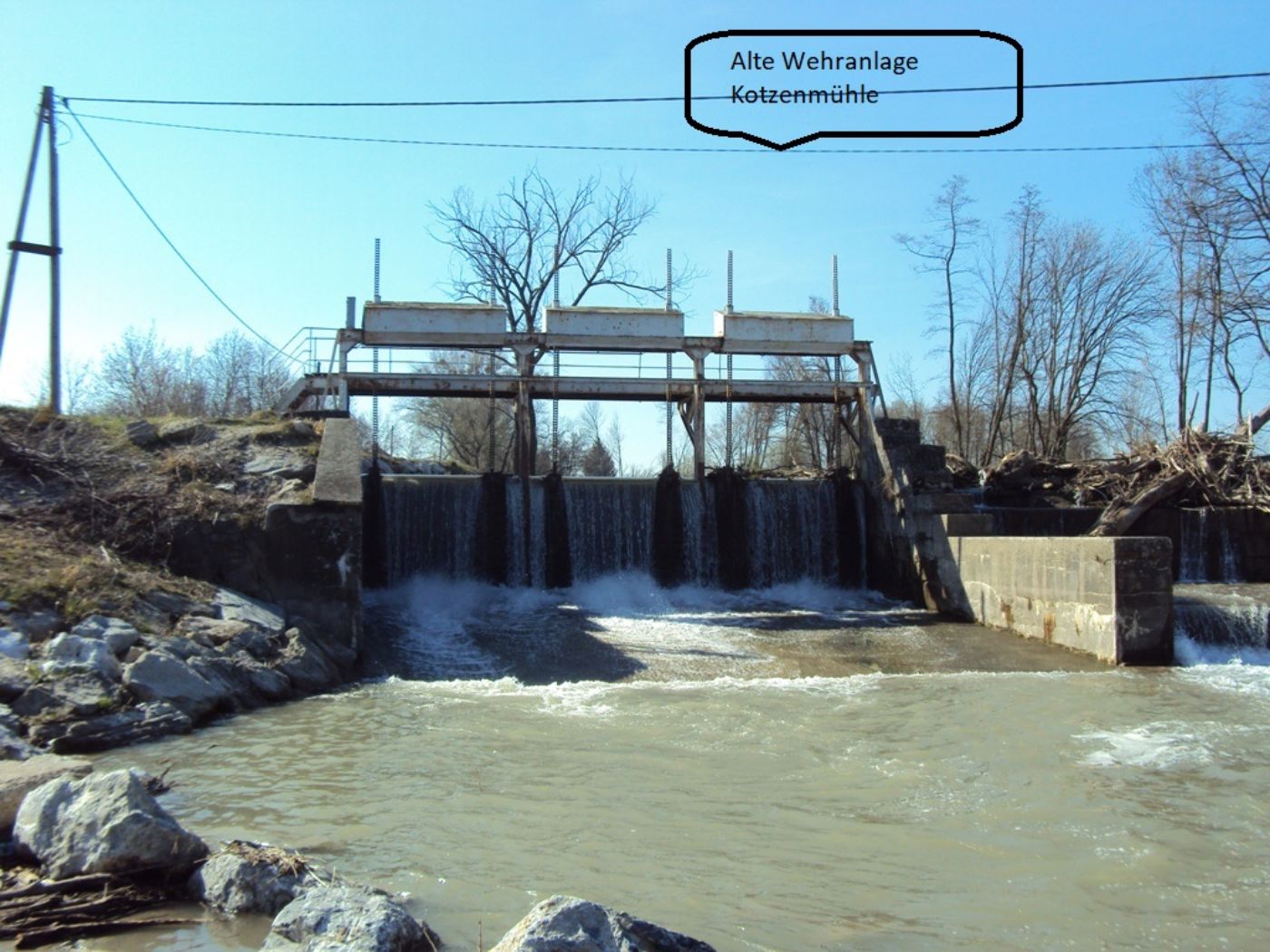 im Hintergrund eine alte Wehranlage vorne Wasser und seitlich grosse Wasserbausteine		