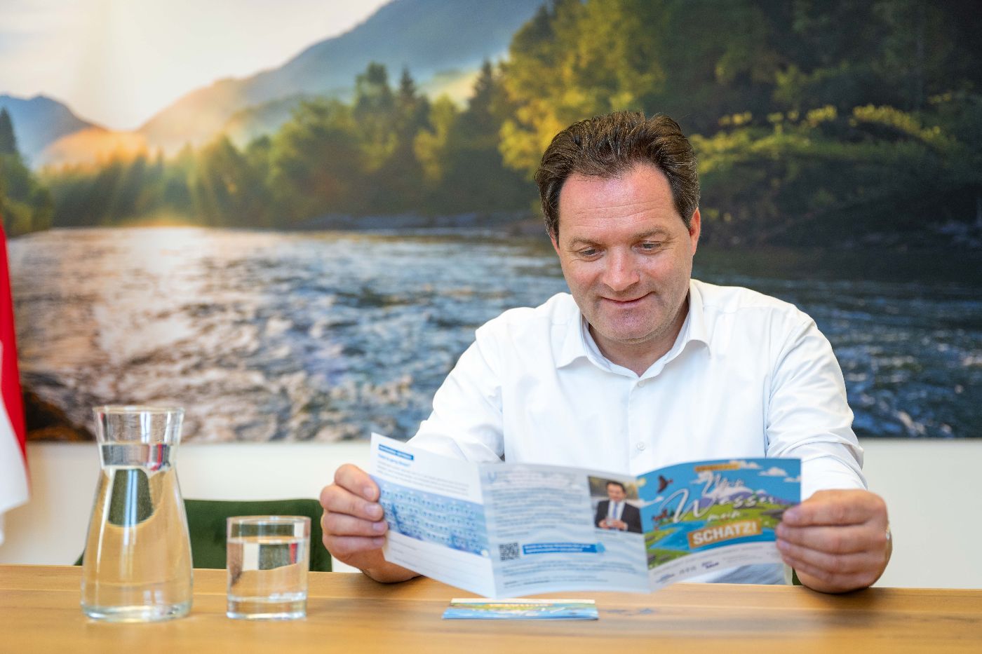 Bundesminister Norbert Totschnig schaut sich den Trinkpass Folder an.