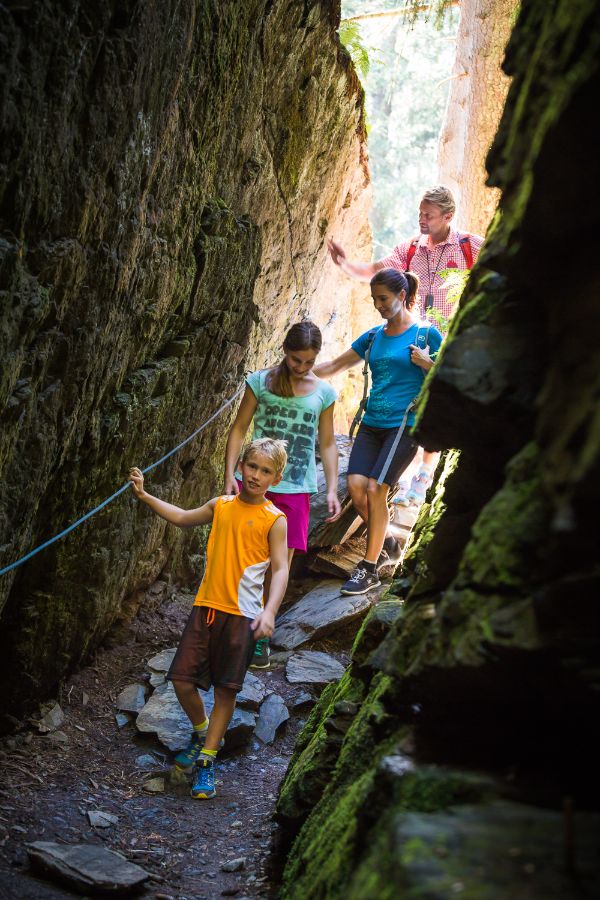 Familie wandert über einen Steig in einer Schlucht des Berges