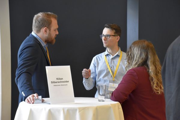 Drei Personen an einem Stehtisch