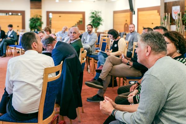 Publikum auf Stühlen unterhält sich