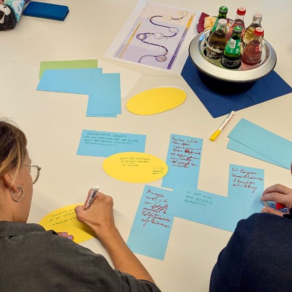 Eine Frau schreibt Diskussionsergebnisse auf bunte Karten. 