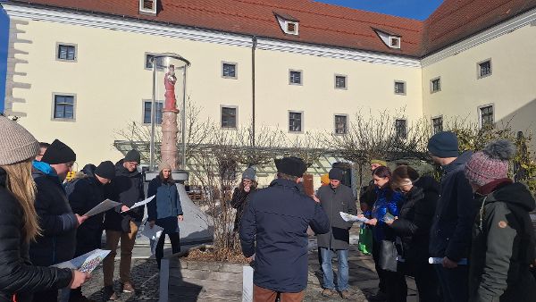 Exkursionsgruppe steht im Halbkreis auf einem Platz