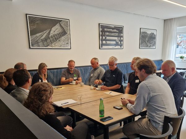 Mehrere Personen sitzen an einem Tisch und diskutieren miteinander. 