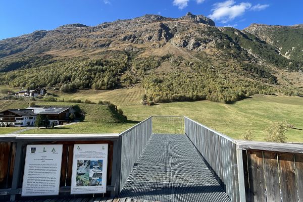 Blick von einer Holzterrasse auf die umliegenden Berge 