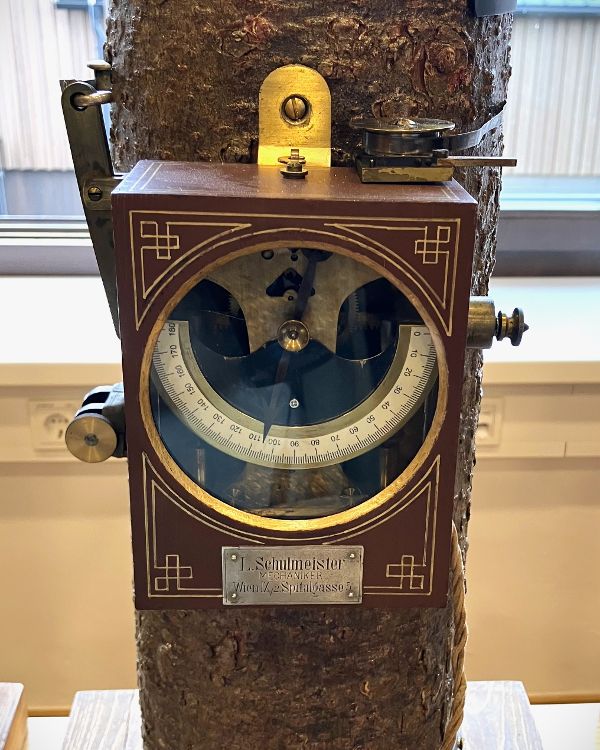 Ein historisches Holzmessgerät an einem Baumstamm.