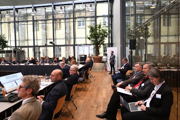 Großansicht, in der man viele Teilnehmerinnen und Teilnehmer während des Meetings aufmerksam zuhören sieht. 