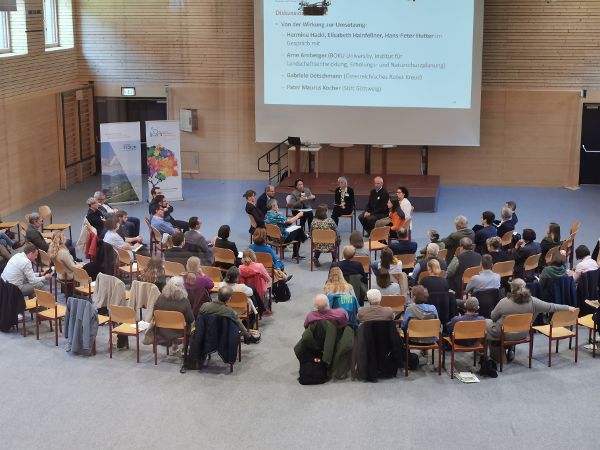 Beim Regional Policy LAb sitzt eine Arbeitsgruppe im Sesselkreis, rundherum sitzen einige weitere Teilnehmer:innen.