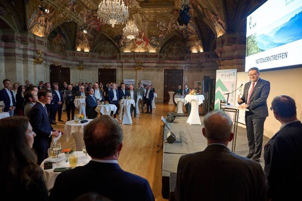 Blick in den Saal, links das Publikum bei Stehtischen, rechts die Bühne, auf der Minister Totschnig eine Rede hält.