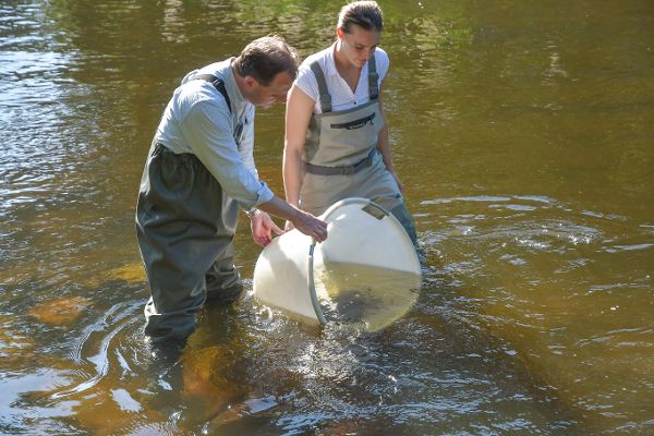 zwei Fischer im Wasser in der Mitte ein weißes Gefaess zum Fischefangen