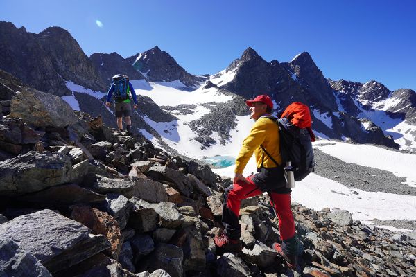 Ein Foto von zwei Bergsteigern an einem sonnigen Tag in den Alpen am Gletscher.